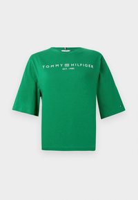 Πράσινο βαμβακερό T-shirt με στρογγυλή λαιμόκοψη και κοντά μανίκια, με λευκή επιγραφή "TOMMY HILFIGER EST. 1985" στο μπροστινό μέρος.