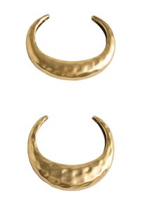 Dwie młotkowane bransoletki z metalu w tonacji złota o otwartym wzorze, z gładkimi brzegami i subtelnym teksturowanym wykończeniem. Każda ma zakrzywiony kształt.