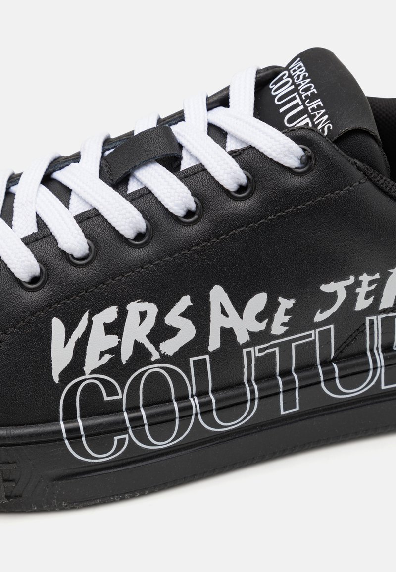 Zapatilla negra con cordones blancos, con una atrevida marca en blanco y negro. Material de cuero suave y suela de goma texturizada.