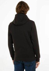 Felpa nera con cappuccio realizzata in morbido cotone misto, con una vestibilità affusolata, dotata di cappuccio regolabile con coulisse e polsini e orlo ribattuti.