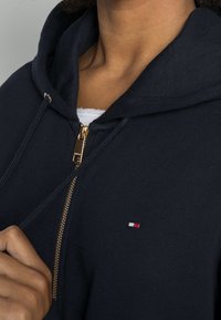 Felpa con zip navy in cotone, con zip dorata, polsini a coste e un piccolo logo multicolore sul lato sinistro del petto.