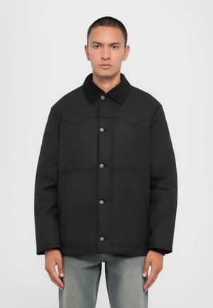 Black padded jacket with a corduroy collar, front button closure, and two large pockets. Smooth fabric with subtle stitching detail.