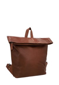 Zaino in pelle marrone con patta pieghevole, manico superiore, spallacci regolabili e dettagli in metallo argentato. Texture liscia con cuciture visibili.