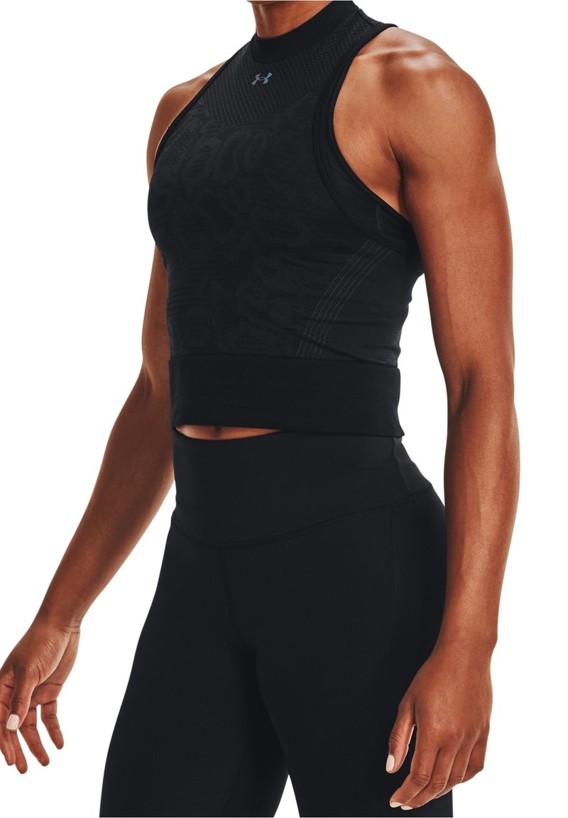 Personne athlétique portant un haut de sport noir moulant sans manches et un legging noir taille haute, debout les bras détendus le long du corps.