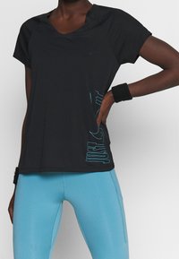 Svart atletisk t-shirt med korta ärmar, med en turkos "JUST DO IT"-logotyp på sidan, matchad med ljusblå leggings.