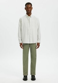 Ανοιχτόχρωμο ριγέ πουκάμισο με κουμπιά, μακρύ μανίκι, με τσέπη στο στήθος. Συνδυάζεται με απλές ελαιόχρωμες παντελόνες και μαύρα παπούτσια.