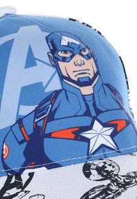 Blue cap featuring a graphic of a superhero with a shield. The underside displays a pattern of various superhero symbols and characters.