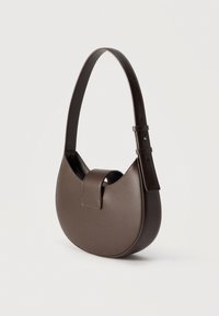 Στρογγυλή τσάντα χειρός από λείο δερμάτινο σε σκούρο καφέ χρώμα, με φαρδιά ρυθμιζόμενη λαβή και κλείσιμο με μαγνητικό καπάκι, απεικονισμένη σε λευκό φόντο.