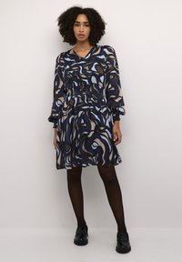 Fließendes Kleid in einer dunklen Farbpalette mit blauen und braunen abstrakten Mustern, langen Ärmeln, gerafftem Taillenbund und knielangem Design.