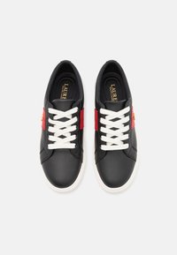 Musta nahkakengät valkoisilla nauhoilla, joissa on punainen raita ja kultaiset yksityiskohdat. Pyöreä varvas ja sileä pinta, sopii rentoon käyttöön.