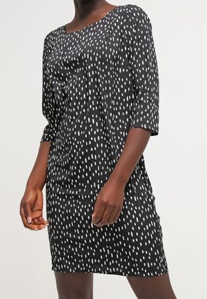 Robe noire à pois blancs verticaux, avec un décolleté bateau et des manches trois-quarts, fabriquée dans un tissu lisse, coupe décontractée.