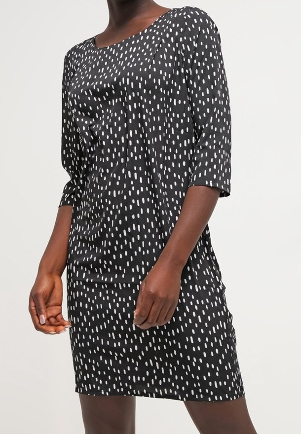 Robe noire à pois blancs verticaux, avec un décolleté bateau et des manches trois-quarts, fabriquée dans un tissu lisse, coupe décontractée.