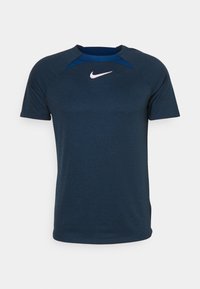 Marinblå Nike idrottströja med korta ärmar, raglan-design och kontrasterande halsringning. Har en liten vit logotyp på bröstet.