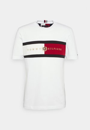 Wit katoenen t-shirt met een horizontaal gestreept ontwerp in zwart, rood en crème, met het "TOMMY HILFIGER"-logo in goudkleurige borduursels.