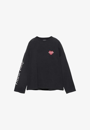 Fekete hosszú ujjú ing kis piros szívvel és "Heart Thief" felirattal a mellkason, fehér szöveges felirattal a jobb ujján lefelé futva.