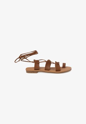 Brown leather flat sandals with multiple straps, ankle ties, and a flat wooden sole. Smooth texture with a minimalistic design.