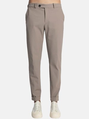 Pantaloni beige a gamba affusolata con frontale piatto, tasche laterali e chiusura a bottone singolo. Orli a risvolto abbinati a sneakers bianche.