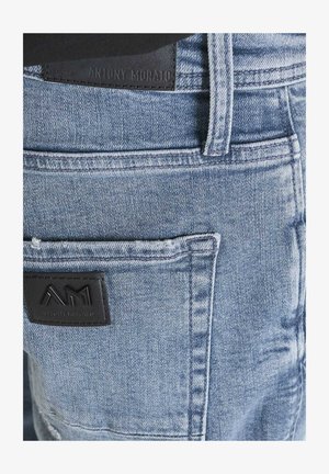 Jeans in denim azzurro chiaro con passanti per cintura visibili e toppe in pelle nera con il logo "Antony Morato" impresso sulla cintura e sulla tasca.
