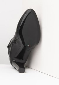 Black leather high-heeled boot featuring a pointed toe, smooth texture, a curved silhouette, and a distinctive block heel design.