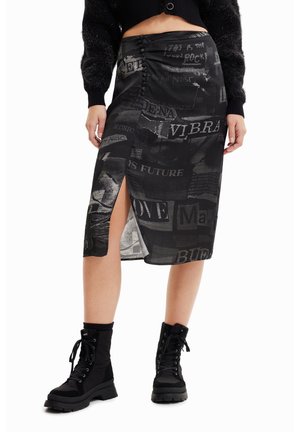 Jupe midi noire avec une fente haute, présentant un tissu texturé orné de divers imprimés graphiques et d'éléments textuels.