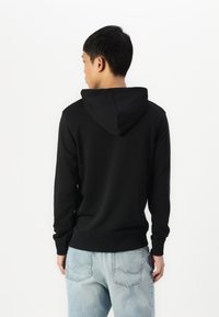 Schwarzer Hoodie mit Kängurutasche, gerippten Bündchen und Saum. Baumwollmischgewebe. Die Rückansicht zeigt ein minimalistisches Design und eine angenähte Kapuze.
