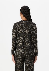 Langermet topp i svart og brunt leopardmønster, med rund hals og avslappet passform. Mykt, lett stoff med en glatt tekstur.