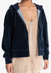 Navy corduroy hoodie with a zip front and gray striped lining. Features a hood, long sleeves, and ribbed cuffs. Smooth texture.