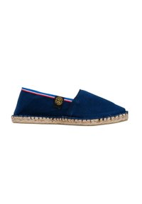 Espadrille en toile marine avec une semelle en jute tressé, arborant un petit badge logo et des rayures rouges et blanches le long du bord d'ouverture.