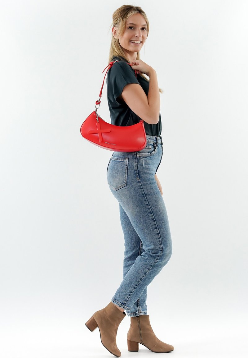 Borsa a tracolla in pelle rossa con forma curvata e motivo a croce in rilievo. Presenta una tracolla e una superficie liscia.