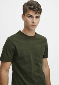 Olivengrønn t-skjorte med korte ermer laget av mykt stoff, med rund hals og en tettsittende silhuett med subtil tekstur.