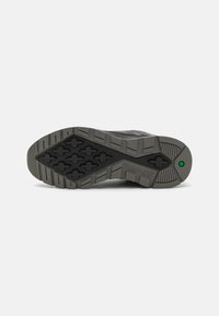 Timberland shoe sole with patterned rubber, featuring deep grooves for traction, in black and gray tones. Includes green accent detail.