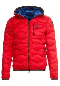 Červená prošívaná bunda s černým zipem, modrou podšívkou, kapsou na hrudi a logem na levém rukávu.