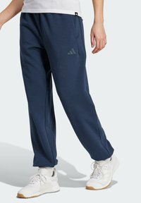 Marineblauwe joggingsbroek gemaakt van zachte stof, met een elastische tailleband, zijzakken en een diagonale logoaccent op de linker bovenbeen.