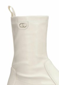 Witte leren enkelboot met een zachte textuur, voorzien van een ronde zilveren hardware-detail en een gestikte naad langs de zijkant.