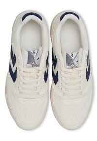 Weiße Sportschuhe mit dunkelblauen Chevron-Akzenten, durchlöchertem Zehenbereich, strukturiertem Stoffinnenraum und flachen Schnürsenkeln. Entworfen für Komfort und Sport.