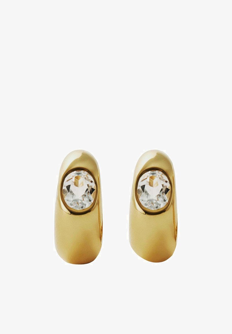 Un par de pendientes de aro de oro pulido, cada uno engastado con una gema redonda transparente en el centro, sobre un fondo blanco.
