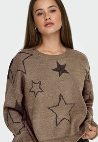 Brązowy sweter z dzianiny z ciemnymi wzorami w gwiazdki, okrągłym dekoltem i luźnym krojem z teksturowanym ściegiem. Cechuje się wyrazistym, casualowym stylem.