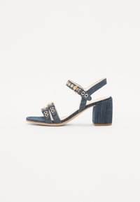 Denim høyhælte sandal med blokkheel, åpen tå og ankelstroppe. Har gullfarget detaljer og flere øyeletsdekorasjoner.