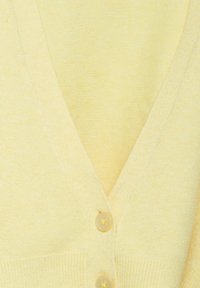 Ljusgul cardigan med V-ringad design, mjuk textur och tre runda knappar på framsidan för stängning.