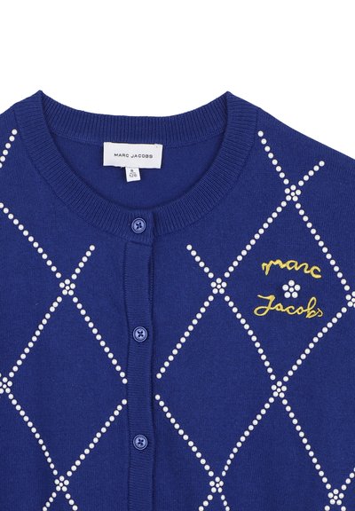Μπλε ζακέτα Marc Jacobs με λευκές χάντρες που μοιάζουν με μαργαριτάρια σχηματίζοντας διαμαντένιο σχέδιο, κίτρινο κεντημένο λογότυπο Marc Jacobs και μπλε κουμπιά μπροστά.