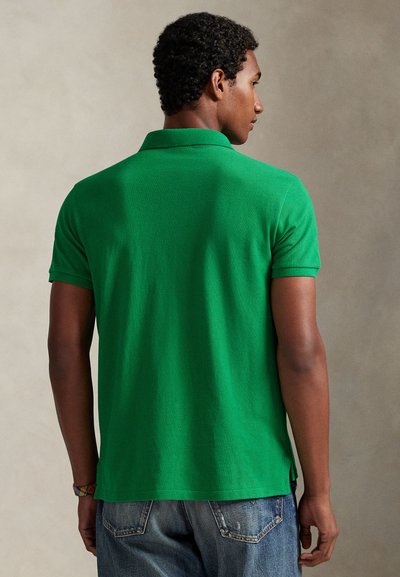 Πράσινο πουκάμισο πόλο με υφασμάτινη υφή, κοντά μανίκια και ριμπ γιακά. Το πουκάμισο έχει ίσια ραφή στο τελείωμα και πλαινές σχισμές στο κάτω μέρος.