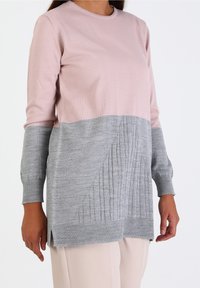 Maglione a maglia rosa chiaro e grigio con maniche lunghe, polsini a coste e una sezione inferiore grigia testurizzata caratterizzata da linee verticali.