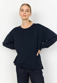 Navy blue sweatshirt with a relaxed fit, wide neckline, and long sleeves. Features side slits and soft, textured fabric. Paired with dark jeans.
