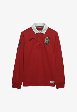 Rode rugbyshirt met lange mouwen, witte kraag, geborduurd wapen op de borst, "Superdry" tekst, mouwpatch en nummer 15 label bij de zoom.
