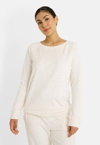 Top de manga larga color crema con patrón de leopardo texturizado, escote redondeado y corte relajado. Tejido suave con ligero elastano.