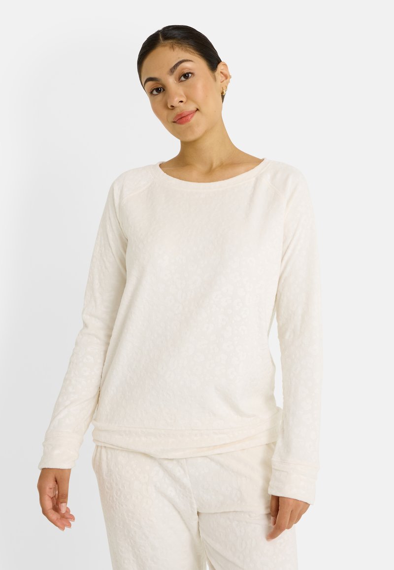 Top de manga larga color crema con patrón de leopardo texturizado, escote redondeado y corte relajado. Tejido suave con ligero elastano.