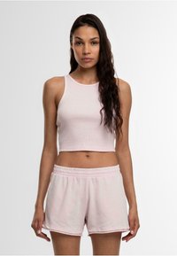 Lichtroze geribde crop top met een ronde halslijn, gecombineerd met lichtroze shorts met elastische taille. Beide stukken hebben een zachte textuur.