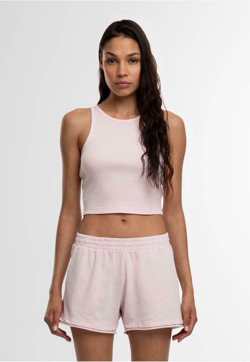 Lichtroze geribde crop top met een ronde halslijn, gecombineerd met lichtroze shorts met elastische taille. Beide stukken hebben een zachte textuur.