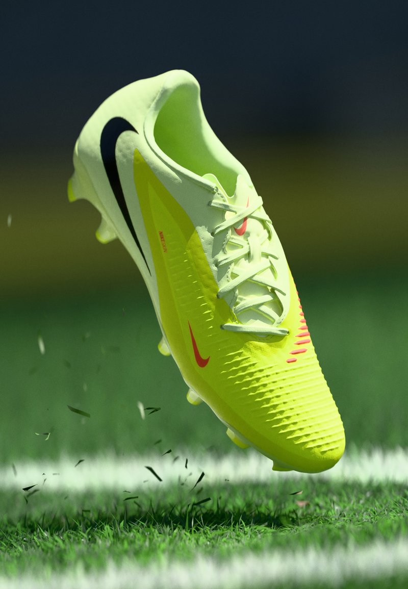Lys gul fodboldstøvle med struktureret overflade, sort swoosh-logo, røde detaljer, snørebånd og synlige studs, svævende over græs.