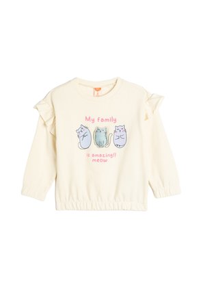 Kremowy sweter z falbaniastymi rękawami, z trzema ilustrowanymi kotami i napisem "Moja rodzina jest niesamowita!! miau" w kolorze różowym.